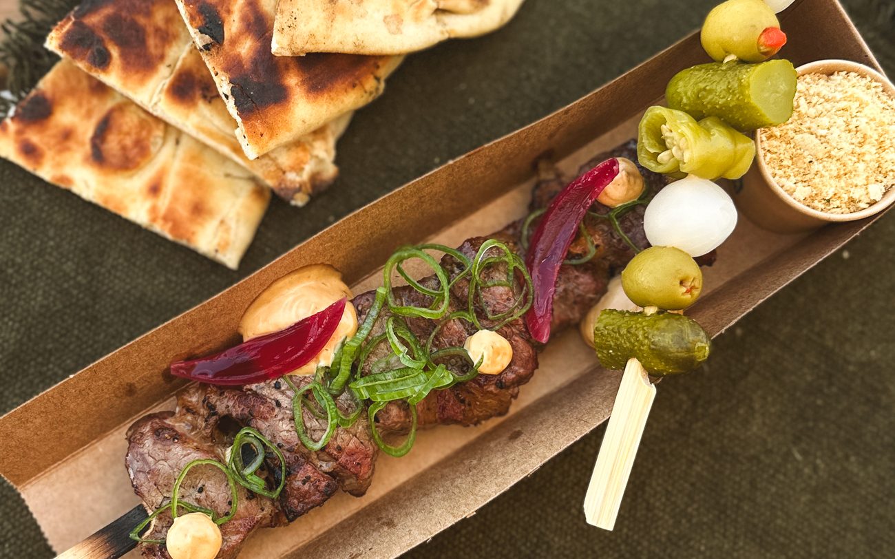 Caixa de street food com espeto de carne, pickles, pão grelhado e farofa