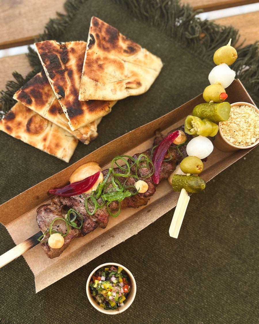Caixa com espetos de carne, pickles, pão grelhado e farofa