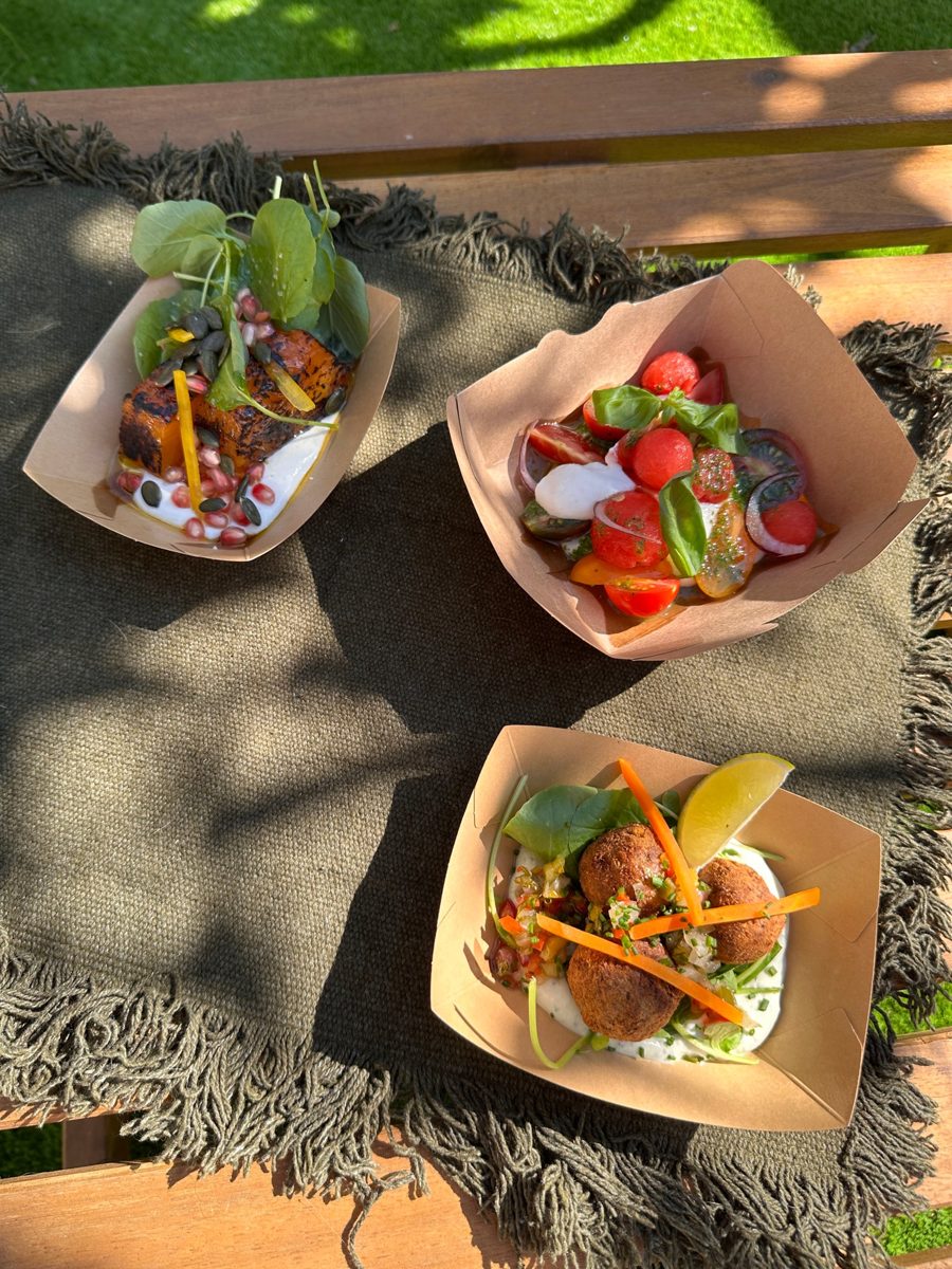 Três pequenos pratos em caixas: abóbora, salada de tomates e falafel