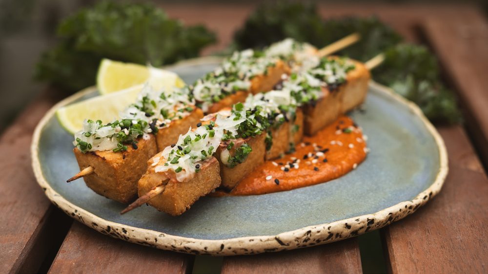 Espetos de tofu e queijo coalho grelhados sobre molho romesco